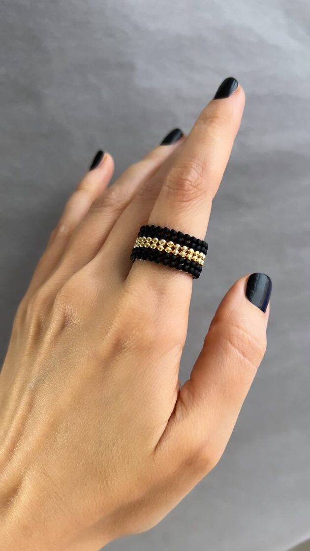 Melns matēts gredzens ar diviem centrāliem zelta akcentiem.