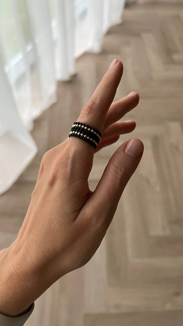 Melns matēts gredzens ar divām izkliedētām zelta detaļām.