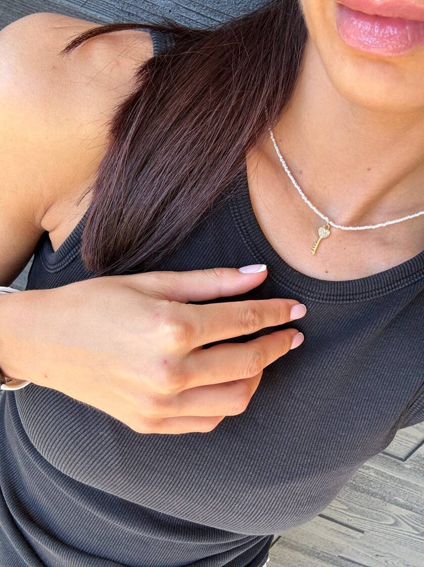 Balts pērļu choker ar lielu atslēgu, elegants un stilīgs aksesuārs.