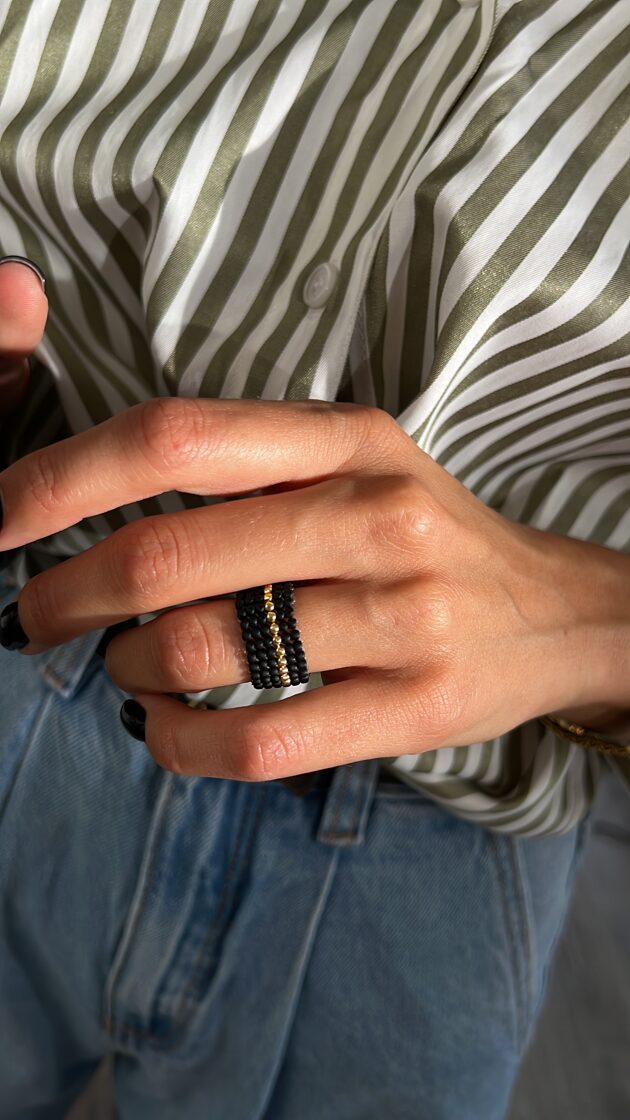 Melns matēts gredzens ar vienu centrālu zelta akcentu.