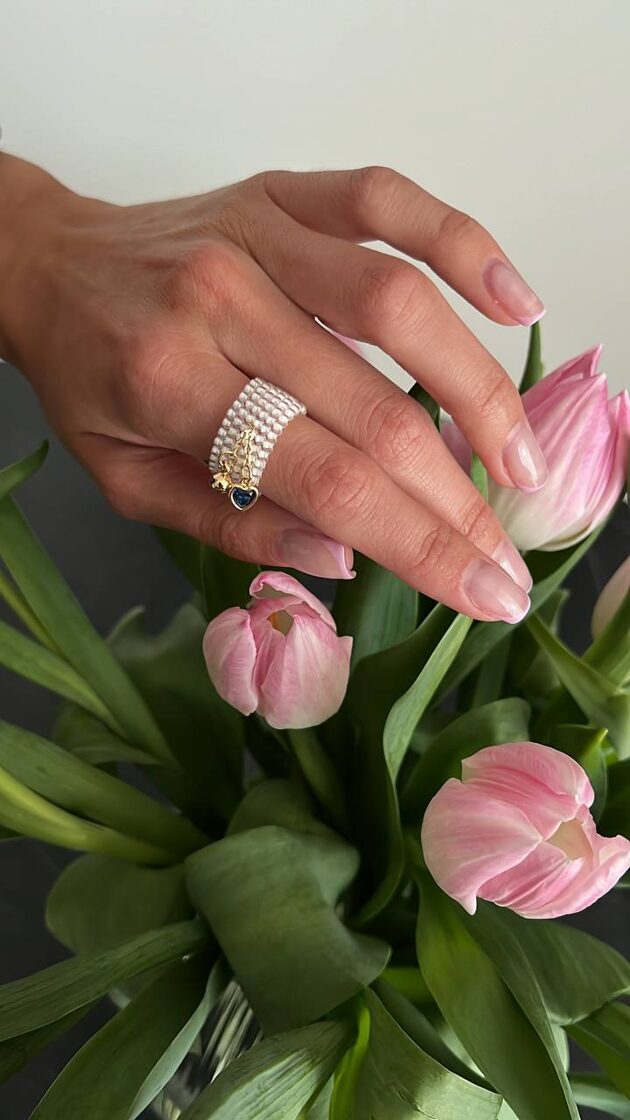 Balts pērļu rotājums ar zilu sirdi un mazu sfēru.