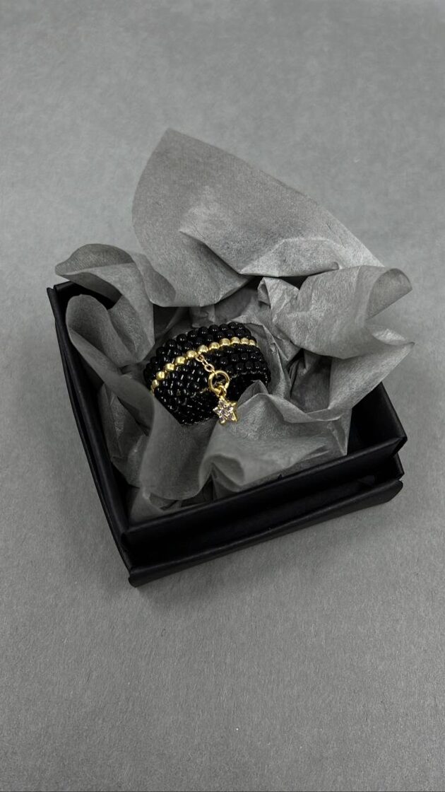 Melns skatījums ar zeltītu akcentu un mazu zvaigzni, piešķir elegantu un modernu izskatu.