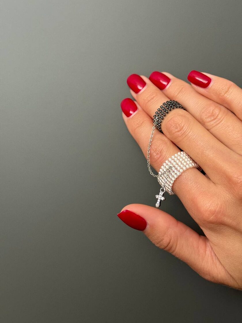 Balts pērļu un grafīta aksesuārs ar mazu krustu dizainā.